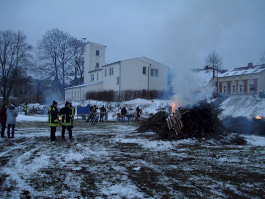 Weihnachtsbaumfeuer - brennende Weihnachtsbäume im Hintergrund die ersten Gäste