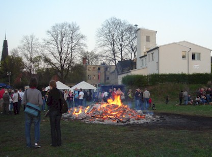 Das Osterfeuer schon etwas heruntergebrannt mit dem ger&auml;tehaus im Hintergrund