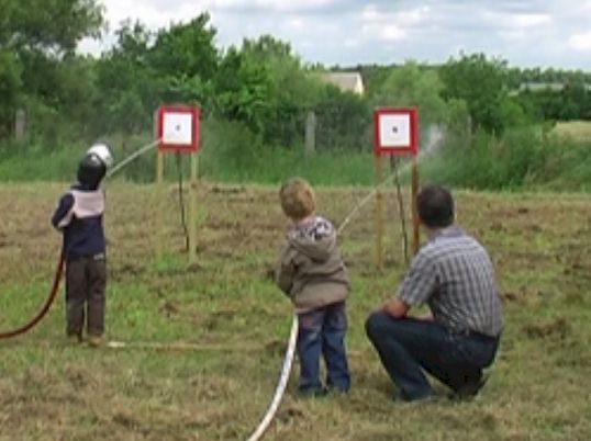 Kinder zielen mit dem Wasserstrahl auf eine Zielscheibe